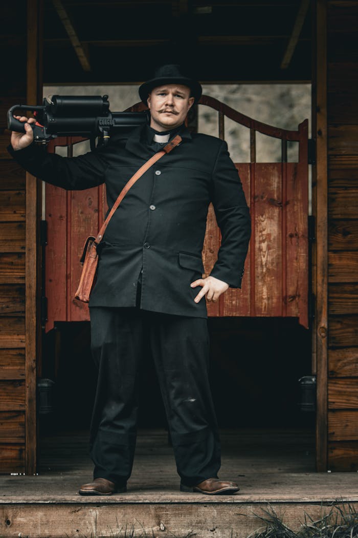 A man dressed in historical attire stands confidently with a machine gun at a saloon entrance.