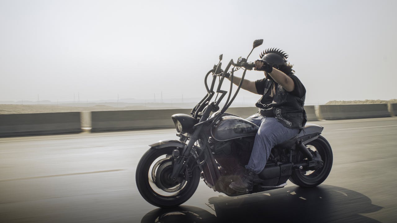 Rider on a custom motorcycle cruising down a highway, showcasing freedom and adventure.