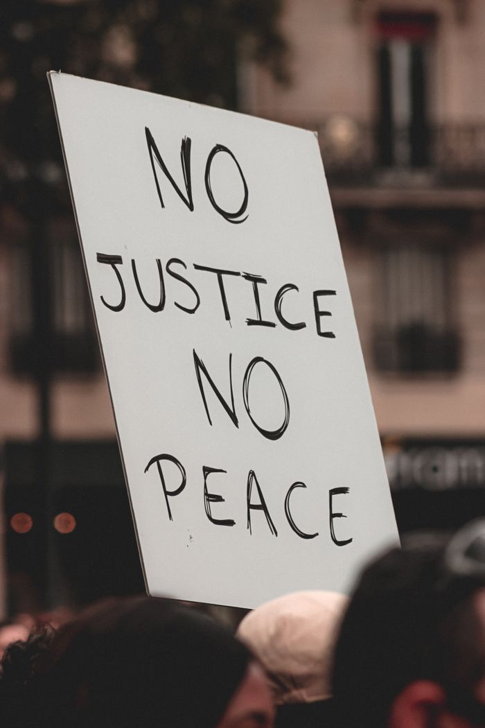 Group of crop peaceful protesters at Black Lives Matter demonstration with handwritten poster reading No Justice No Peace